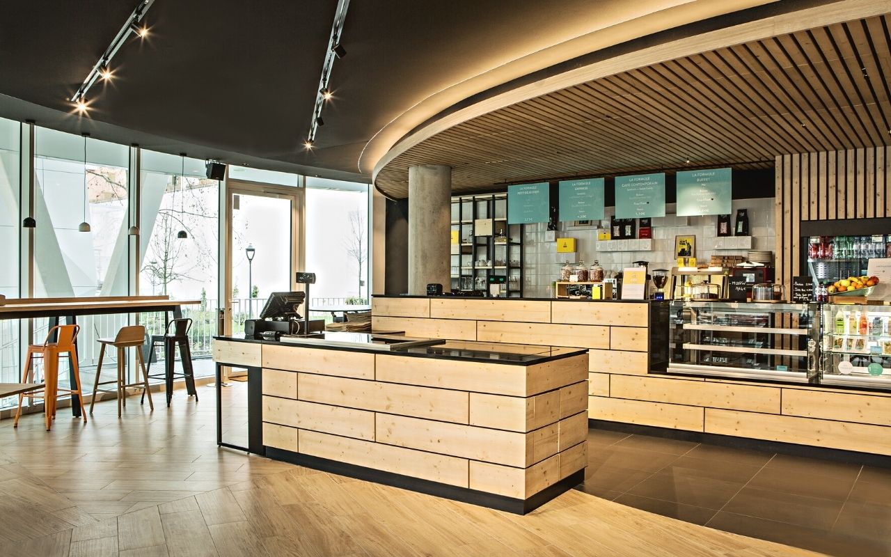 Cafétéria du siège social de Danone dans l'immeuble Convergence avec libre service et décorations en bois; bureauw designés par le studio d'architecture d'intérieur jean-philippe nuel