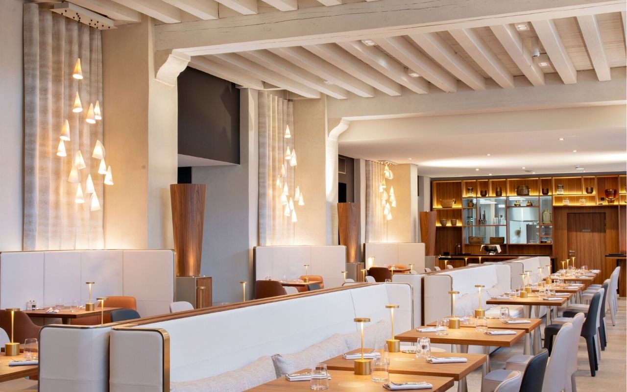 Décoration d'intérieur lumineuse du Restaurant Epona de l'InterContinental Lyon Hotel Dieu avec des tables en bois signée par le studio d'architecture d'intérieur jean-philippe nuel