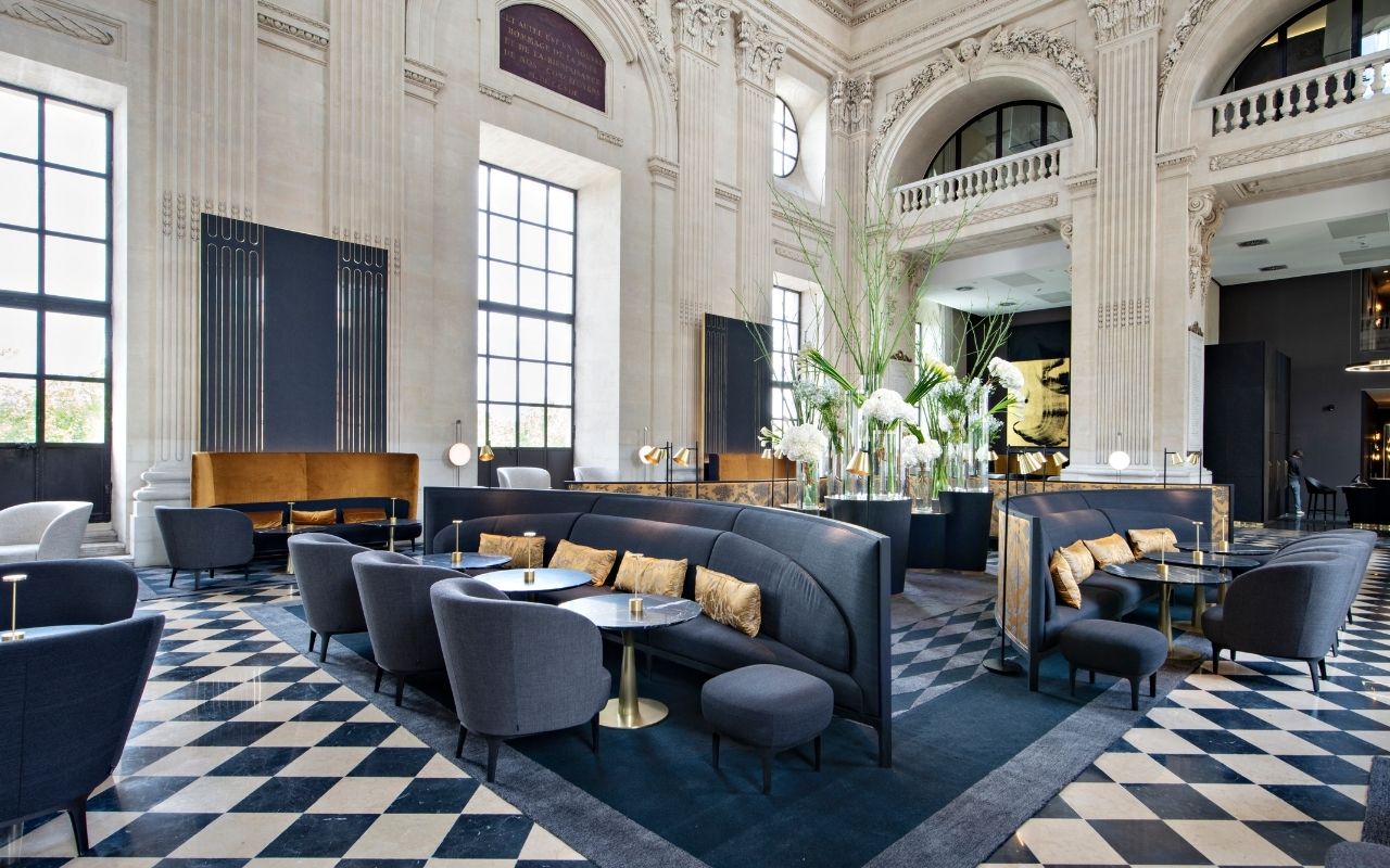 Bar at the InterContinental Lyon Hôtel Dieu decorated with artworks and a checkerboard floor under a majestic dome by the French interior design studio Jean-Philippe Nuel