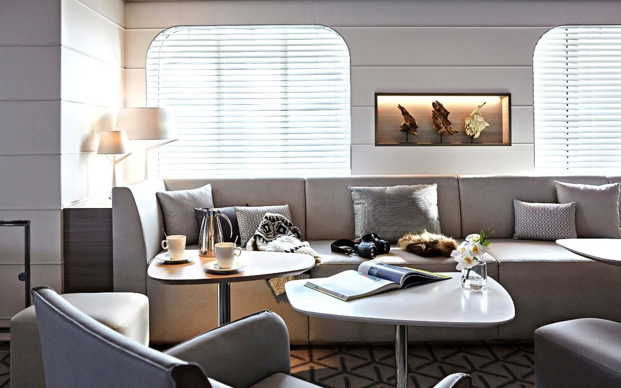 One of the interior lounges of the sister ships of the Ponant company with a maritime and warm atmosphere, luxury cruise ship designed by the interior design studio jean-philippe nuel