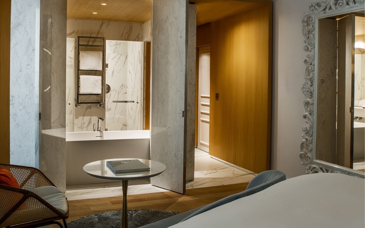 Interior of a room at the Hotel Sofitel Rome Villa Borghese designed by the French interior design studio Jean-Philippe Nuel with a decoration of warm colors and a view on the bathroom