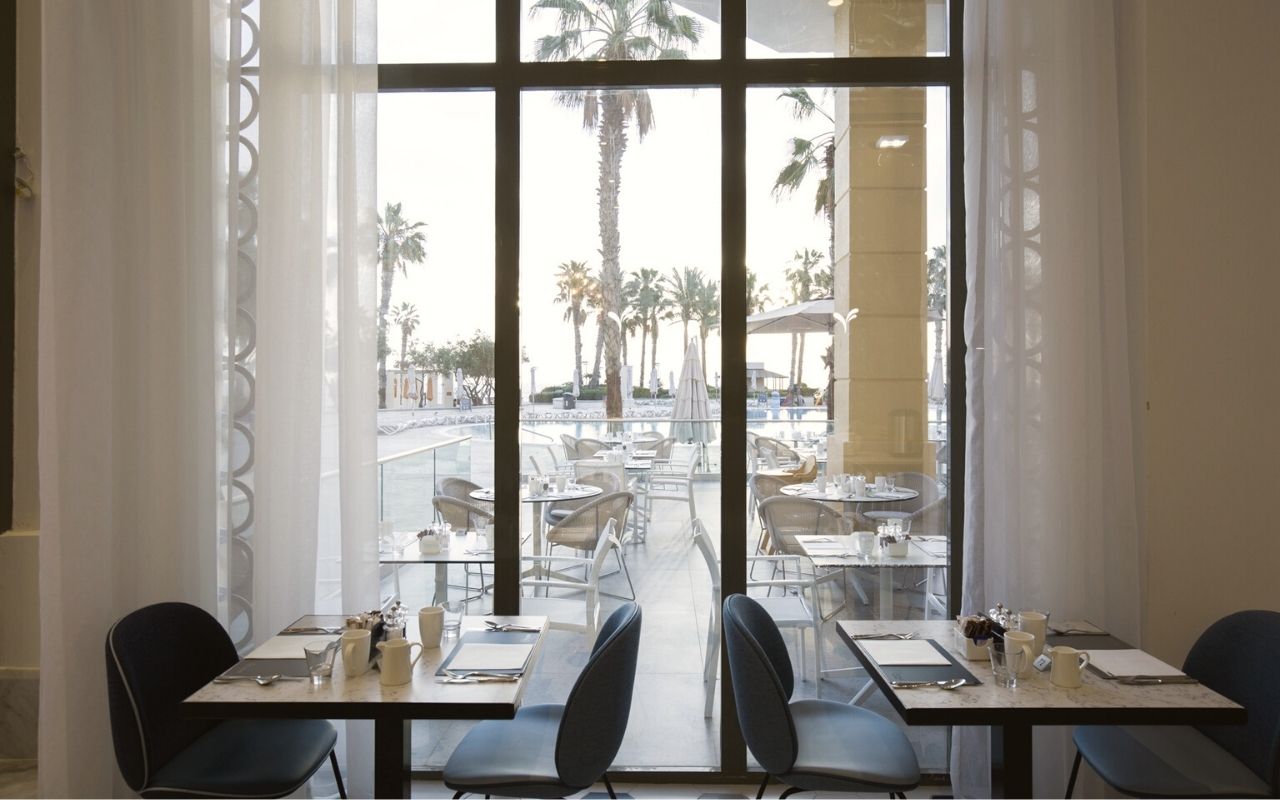 Hilton Malta - luxury hotel designed by the interior design studio jean-philippe nuel - sea view restaurant - large window - palm tree